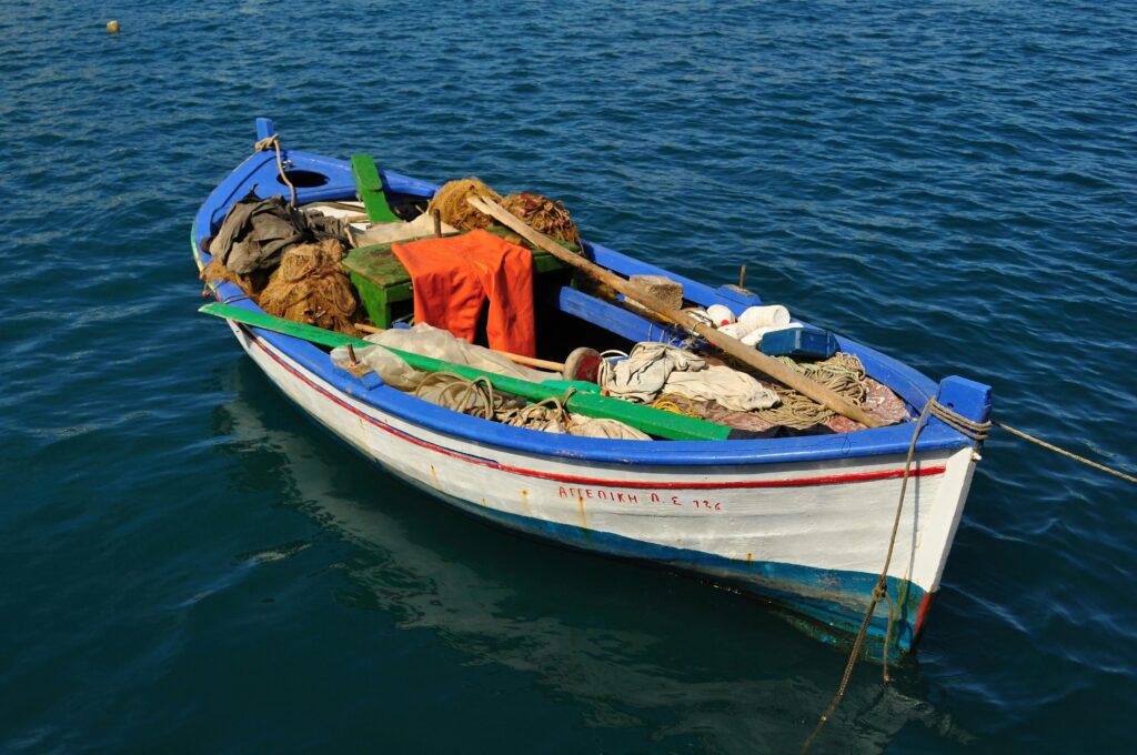 IEEE Young Engineers Conference A vibrant fishing boat filled with nets and gear floats gently on calm blue water.