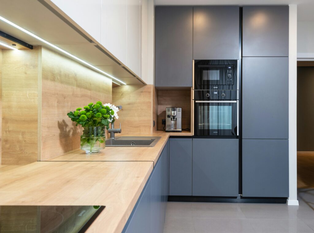 IEEE Young Engineers Conference Creative design of kitchen with flowers in vase on table against coffeemaker and oven built in cupboard at home